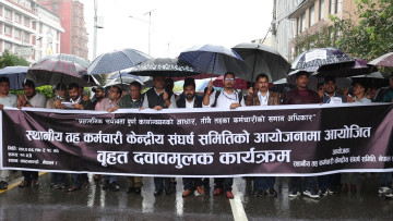 वर्षा भइरहँदा पनि छाता ओढेर आन्दोलन गरिरहेका छन् स्थानीय तहका कर्मचारी (तस्वीरहरू)